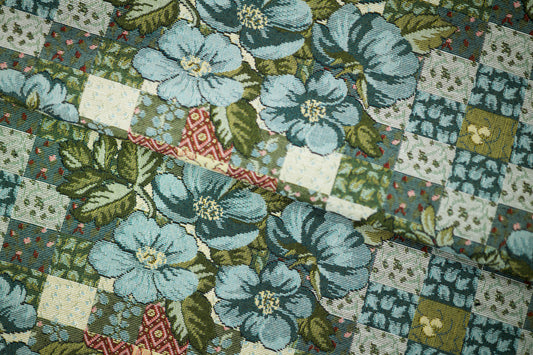 Bunter Möbelstoff mit Patchwork-Optik und blauen Blumen auf hellem Grund – perfekt für kreative Polsterprojekte