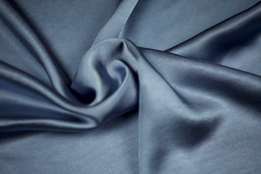 Weich fallender Satinstoff in elegantem Taubenblau mit seidigem Schimmer – drapiert in fließenden Falten