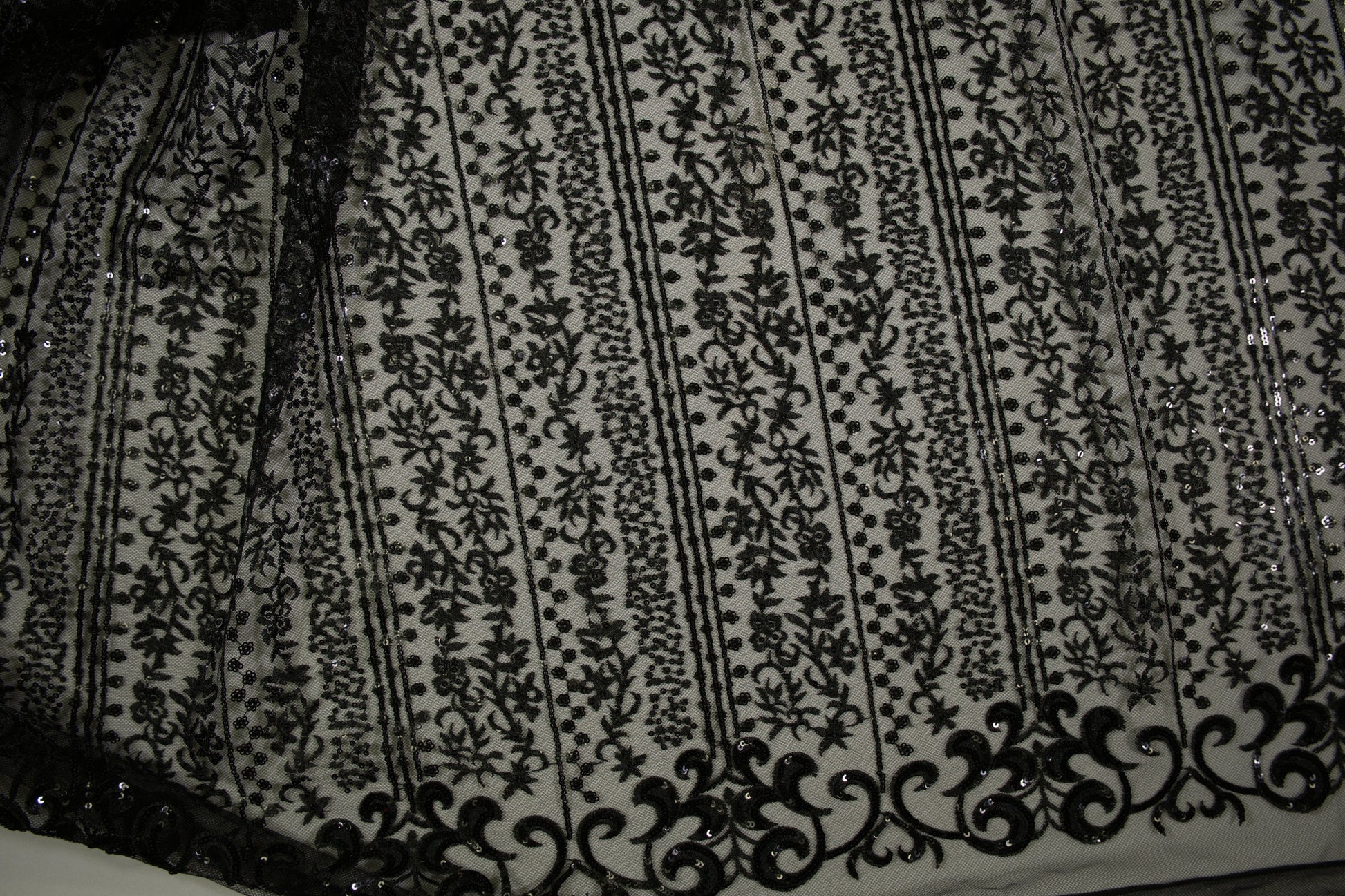 Schwarze Spitzenware auf Tüll mit floralen Streifen und Pailletten in Nahaufnahme