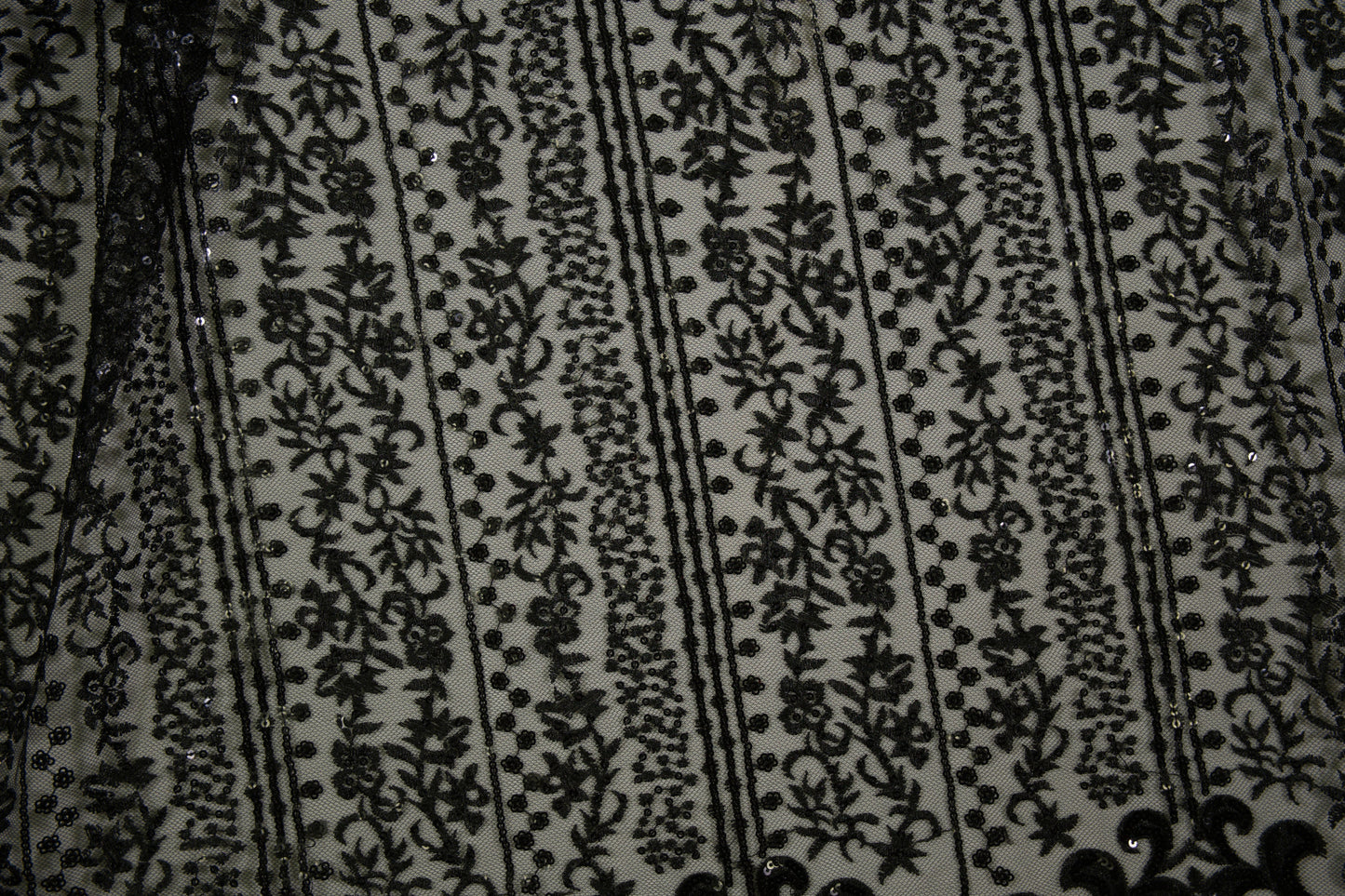 Schwarze Spitzenware auf Tüll mit floralen Streifen und Pailletten in Nahaufnahme