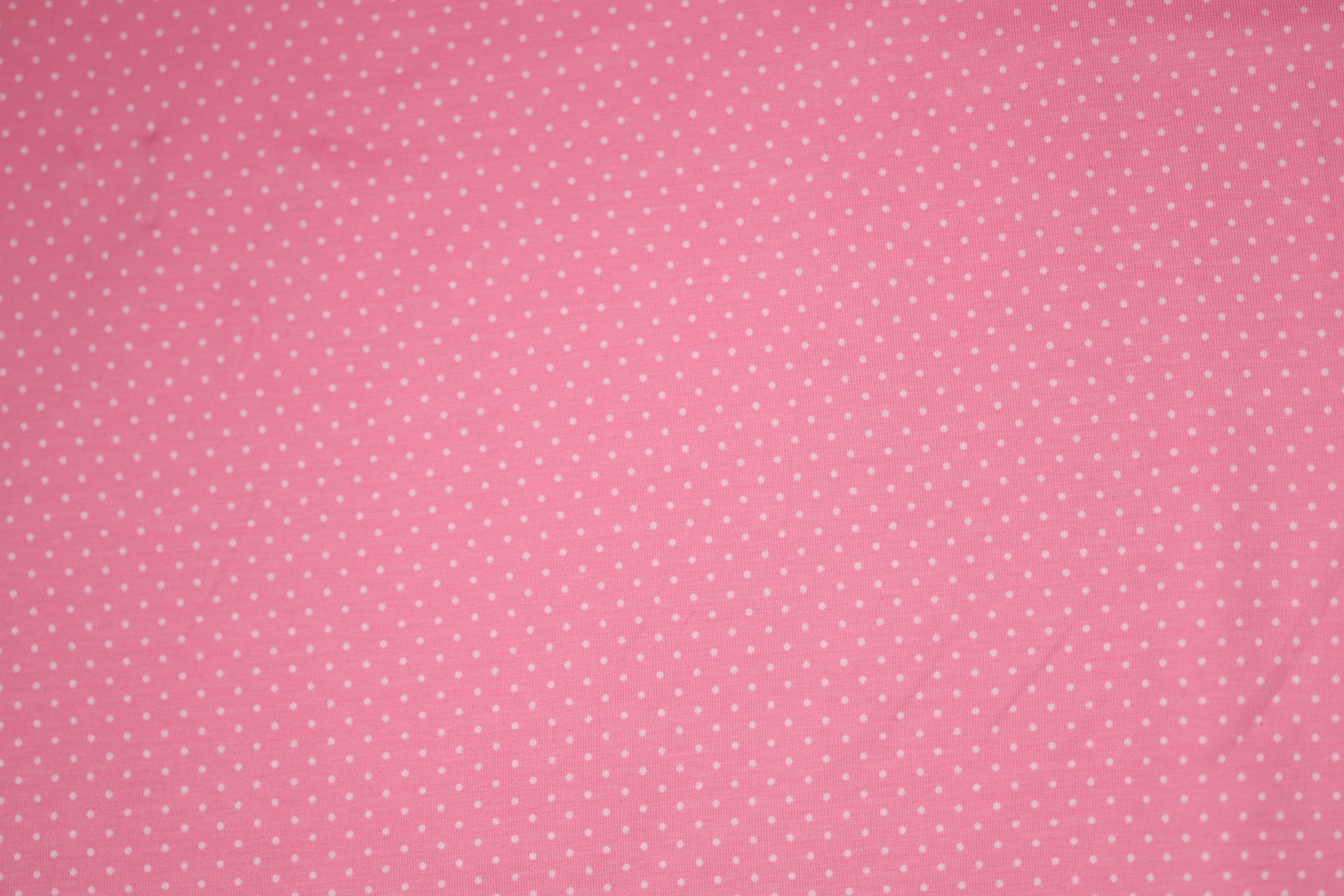 Zartes Punktmuster auf rosa Baumwollstoff – ideal für Baby- und Kinderkleidung.