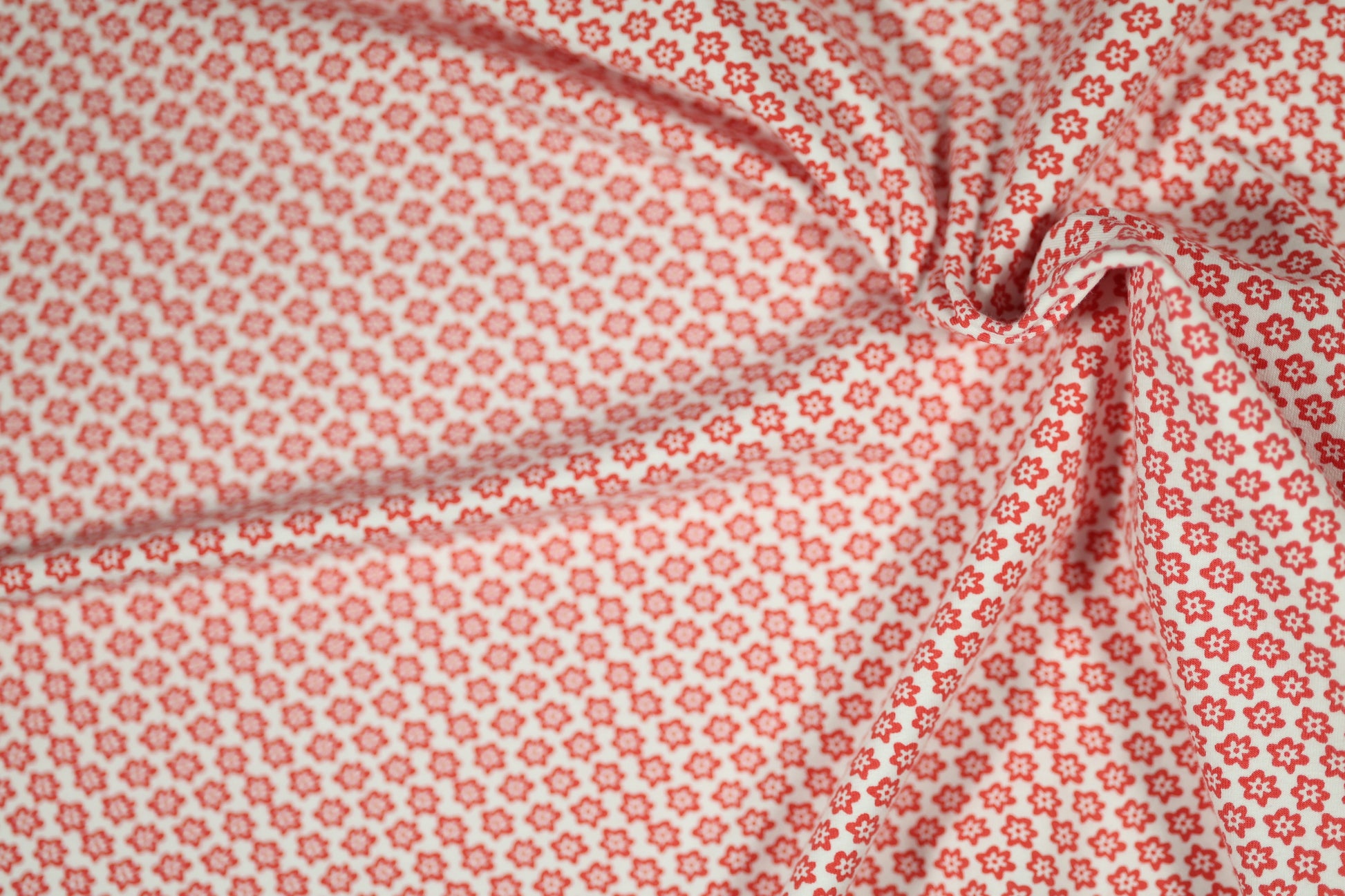 Baumwollstoff mit Motiv: rote mini-blumen auf weiß – weich & kindgerecht.