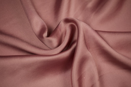 Nahaufnahme eines luxuriösen Satinstoffs in roséfarbenem Altrosa mit edlem Glanz und weichem Faltenwurf – perfekt für elegante Nähideen.
